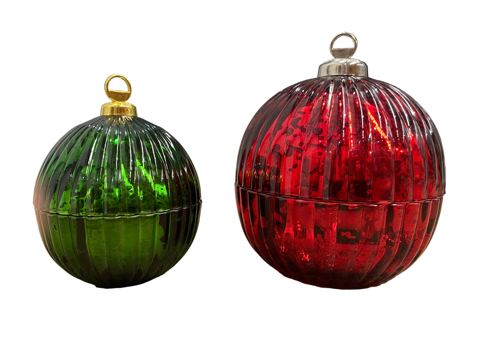 Two ribbed glass ornaments, one green and one red, on a concrete surface.