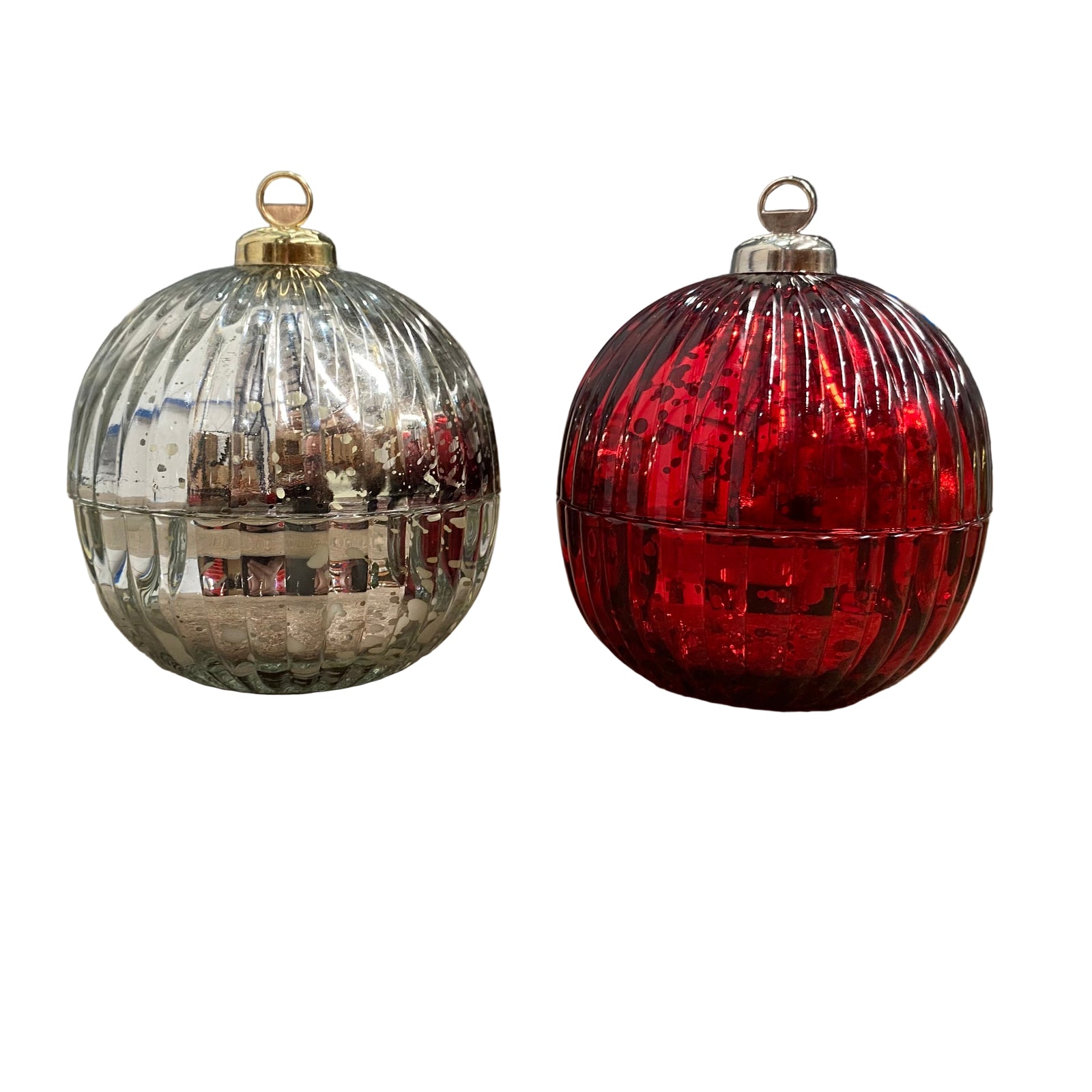 Two glass ornaments, one silver and one red, on a concrete surface with a blurred background.