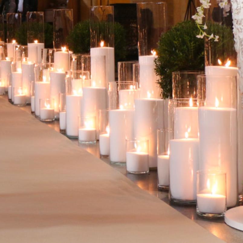 an aisle with sand wax candles lit in glass cylinders